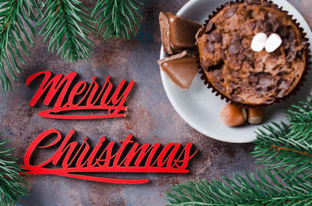 Chocolate muffin, branches fir and Merry Christmas inscription. Xmas time. Selective Focus. Copy space.の写真素材