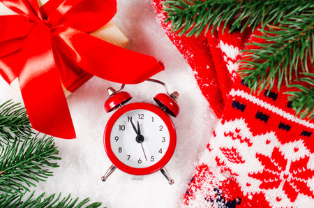 New Year's clock. Xmas decorations, gift box and warm scarf on snow. Christmas background or greeting card.の写真素材