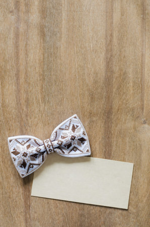 Embroidered Bow Tie and Empty Card on Wooden Brown Background. Father's day Concept. Rustic Styleの写真素材