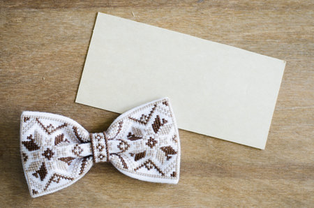 Embroidered Bow Tie and Empty Card on Wooden Brown Background. Father's day Concept. Rustic Styleの写真素材