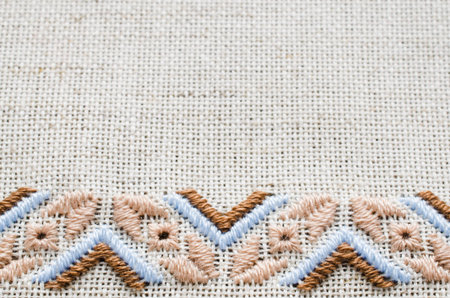 Slavic cross stitch by brown and beige threads. Design of ethnic pattern. Embroidery texture.