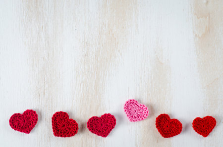 Happy Valentine's Day concept. Background with row border of red knitted hearts on rustic white wooden table. Greeting card mockup, copy space, top view.の写真素材