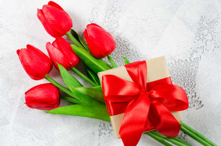 Bouquet of red tulips and gift box on white background. Spring flowers. Spring background. Greeting card for Valentine's Day, Woman's Day and Mother's Day. Top view, copy space.の写真素材