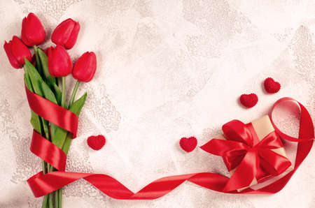 Bouquet of red tulips, gift and decorative hearts on white background. Spring flowers. Spring background. Greeting card for Valentine's Day, Woman's Day and Mother's Day. Top view, copy space.の写真素材