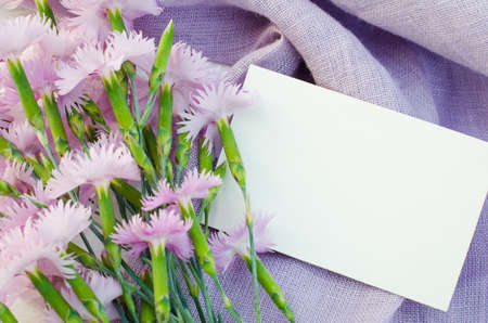 Delicate flowers and empty greeting card. Holiday background. Flat lay style, top view.の写真素材