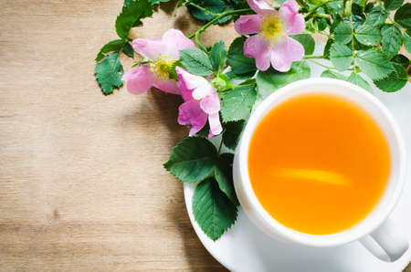 White cup of morning tea with lemon and delicate flowers on wooden rustic table. Cozy breakfast copy spaceの写真素材