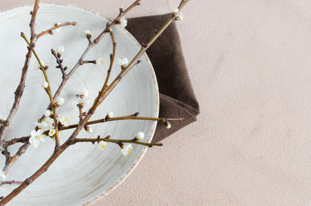 Spring table setting in beige color with flowering branches. Concept Spring, Easter or Mother's Day. Holidays background with copy space. Top view.の写真素材