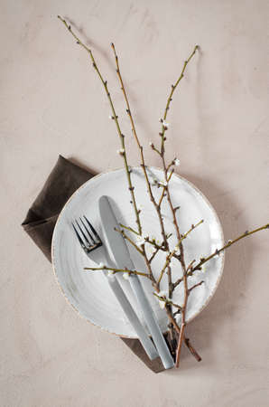 Spring table setting in beige color with flowering branches. Concept Spring, Easter or Mother's Day. Holidays background. Top view.の写真素材