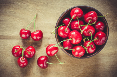 Fresh ripe organic cherries in plate on wooden background. Selective focus, rustic style. Flat lay...