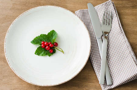 Fresh ripe organic red currant in plate on wooden background. Selective focus, rustic style.の写真素材