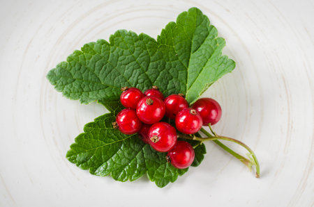 Fresh ripe organic red currant in plate on wooden background. Selective focus, rustic style.