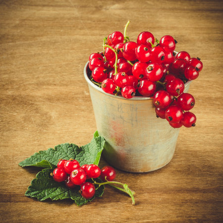 Fresh ripe organic red currant in vintage aluminum cup on wooden background. Selective focus, rustic...