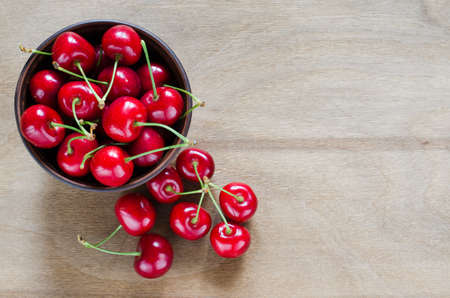 Fresh ripe organic cherries in plate on wooden background. Selective focus, rustic style. Flat lay style, top view.の写真素材