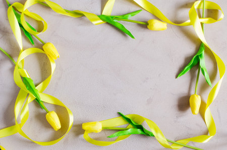 Spring frame of yellow tulips with ribbon. Spring flowers background. Greeting card for Woman's Day...