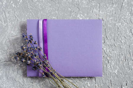Mock up of holiday background. Bunch of lavender flowers and a purple blank greeting card. Copy space for text. Top viewの写真素材