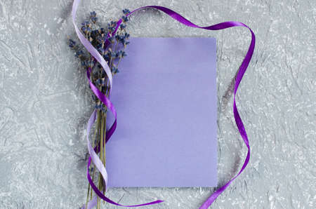 Mock up of holiday background. Bunch of lavender flowers and a purple blank greeting card. Copy space for text. Top viewの写真素材
