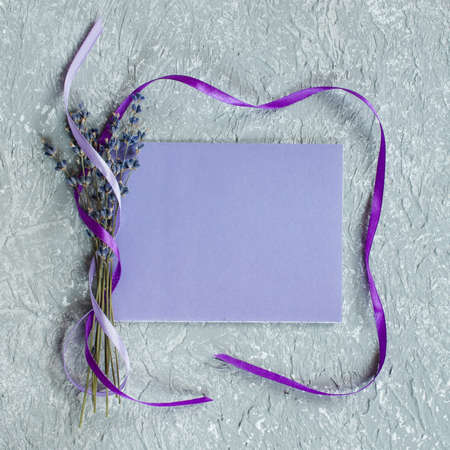 Mock up of holiday background. Bunch of lavender flowers and a purple blank greeting card. Copy space for text. Top viewの写真素材