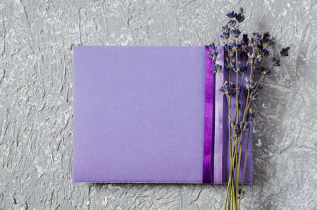 Mock up of holiday background. Bunch of lavender flowers and a purple blank greeting card. Copy space for text. Top viewの写真素材