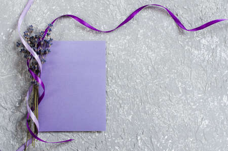 Mock up of holiday background. Bunch of lavender flowers and a purple blank greeting card. Copy space for text. Top viewの写真素材
