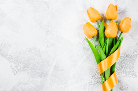 Holiday background with bouquet of yellow tulips and gift box on white background. Spring flowers. Greeting card. Top view, copy space.の写真素材