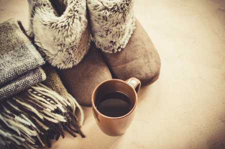 Warm home clothes. Woolen plaid and home slippers and cup of hot beverage.