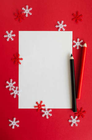 Minimalistic Christmas card mockup with decorative snowflakes and pencils in red color. Empty postcard. Xmas background with, top view with copy space.の写真素材