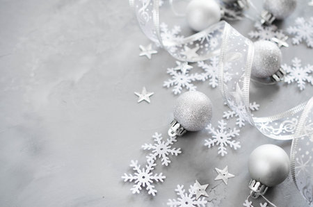 Silver Christmas background. Curly ribbon with decorative balls and snowflakes. Xmas decorations....