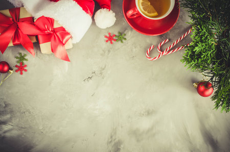 Christmas background. Santa's cap, red christmas present box, cup of hot tea, fir tree branch and...