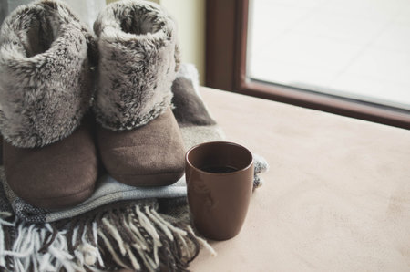 Warm home clothes. Woolen plaid and home slippers and cup of hot beverage.