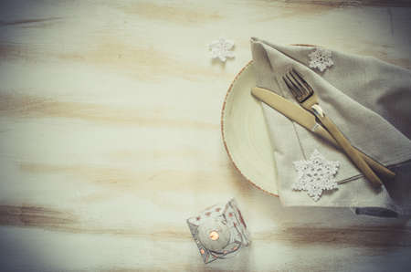 Christmas Table Place Setting With Xmas Decorations at Vintage or Provence Style with Lantern. Silverware with Linen Napkin and Decorative Snowflakes on Rustic Wooden Background. Top View. Copy Space.の写真素材