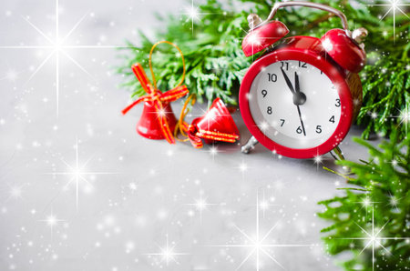 Christmas composition: xmas fir branches, alarm clock and red bells. Christmas still life, greeting postcard.の写真素材