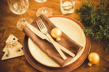 Simple Christmas table place setting on wooden background in vintage or rustic style. Festive table set for christmas or new year dinner.の写真素材