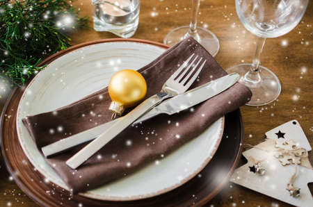 Simple Christmas table place setting on wooden background in vintage or rustic style. Festive table set for christmas or new year dinner. Snow effectの写真素材