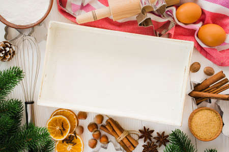 Holiday food background. Gingerbread cookies with cutters, rolling pin and ingredients for baking on white wooden table. Top view. Copy space for christmas recipe.の写真素材