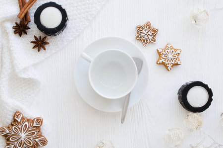 Christmas background. Empty white cup, gingerbread, candles and knitted scarf on a white wooden background. Light still life. Flat lay, top view, copy spaceの写真素材
