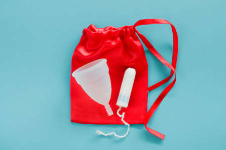 Different types of feminine hygiene products - menstrual cup and tampon on a blue background. Selective focusの写真素材
