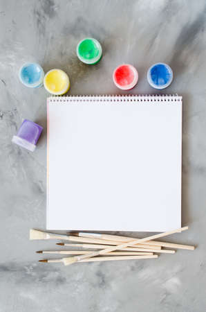 Empty white paper sheet, brushes and paints. Mock up for drawing. View from above. Copy spaceの写真素材