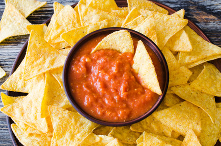 Nachos corn chips with spicy tomato sauce. Mexican food concept. Yellow corn totopos chips with...