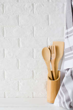 Simple rustic kitchenware: wooden or bamboo cutlery and towel in interior of white kitchen. Rustic style. Home Kitchen Decor.の写真素材