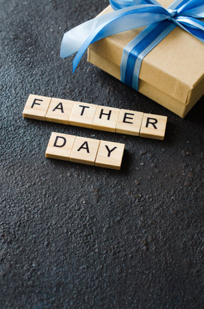 Happy Father's day greeting card with decorated gift box on dark background. Top view.
