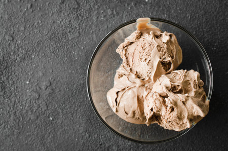 A plate of homemade chocolate ice cream on a dark background. Top view.