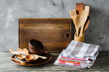 Ceramic plates, wooden or bamboo cutlery, vintage cutting board and towels in interior of kitchen.の写真素材