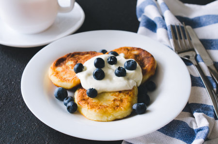 Cottage cheese pancakes or syrniki for breakfast with sour cream or yogurt and blueberry. Healthy...