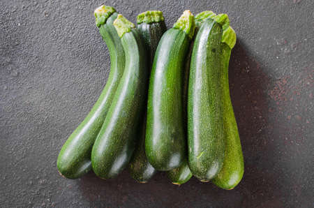 Freshly harvested zucchini, green vegetables on dark background, summer squash. Fresh farm productsの写真素材