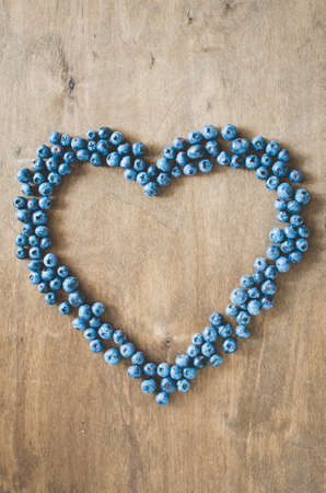 Fresh organic blueberries in form of heart on wooden background. Heart health concept. Disease preventionの写真素材