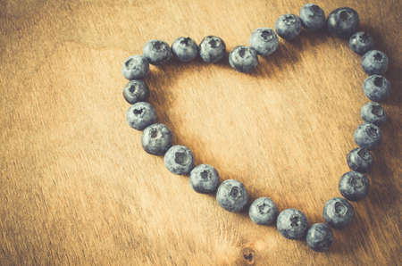 Fresh organic blueberries in form of heart on wooden background. Heart health concept. Disease preventionの写真素材