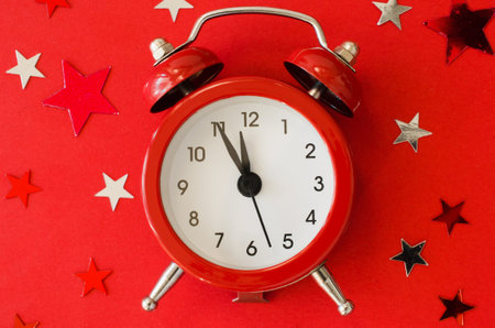 Festive Christmas background with alarm clock on red background in minimal style. New Year...