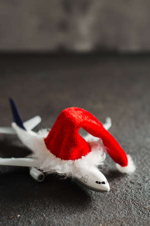 Christmas travel planning. Toy airplane with Santa Claus hat on dark concrete background. Copy Space.の写真素材