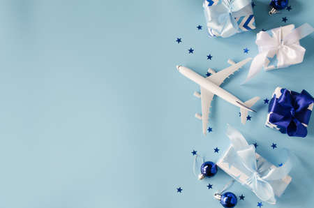 Christmas or New Year travel concept. Toy airplane with passports and gift boxes on blue background. Top view or flat lay. Copy Space.の写真素材