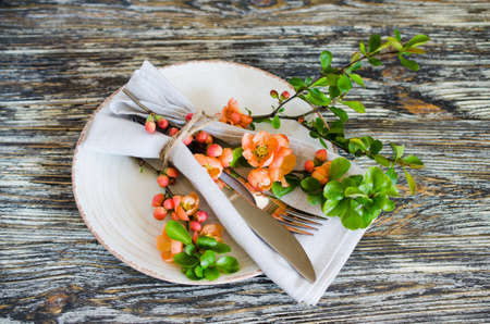 Vintage table setting with delicate flowers on a linen napkin on on rustic shabby table, close-up. Holiday Table Set with floral decorの写真素材
